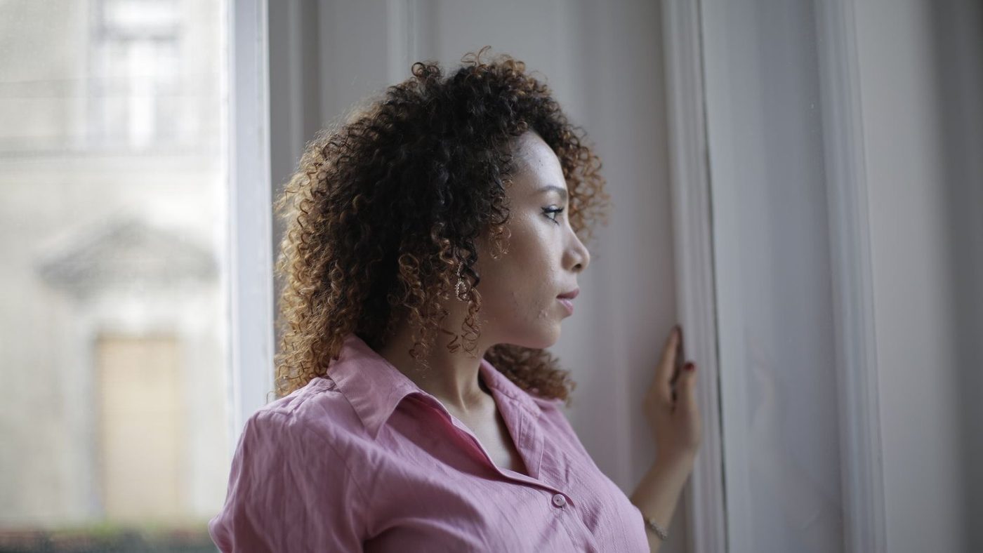A thoughtful woman gazing out a window, conveying a muted, flat mood that an antidepressant cannot fully resolve.